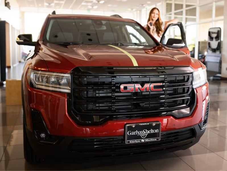 Close-up front view of a red GMC truck inside the dealership showroom