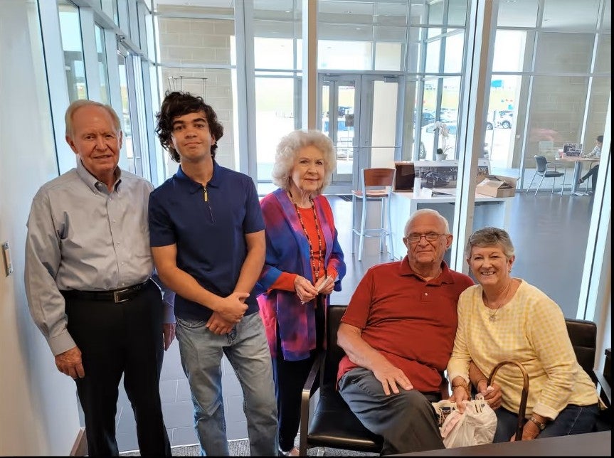 A group of five people standing and sitting inside a room