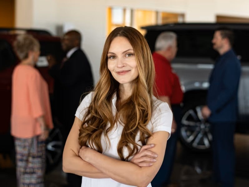 A person standing inside the dealership with arms crossed