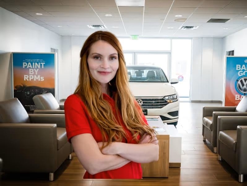 A person standing inside the Volkswagen showroom with arms folded
