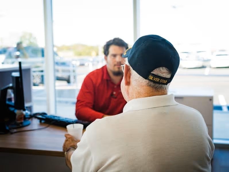 Two people seated at a desk inside the dealership