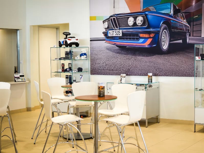 A dealership waiting area featuring white chairs around a round table